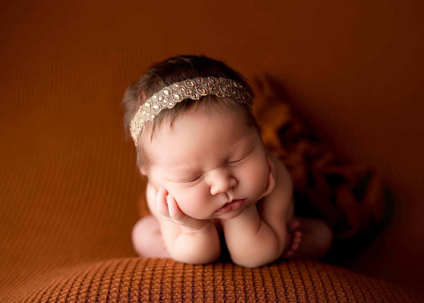 Newborn with gold headband and terracotta backdrop taken in Maria Angeles photography studio
