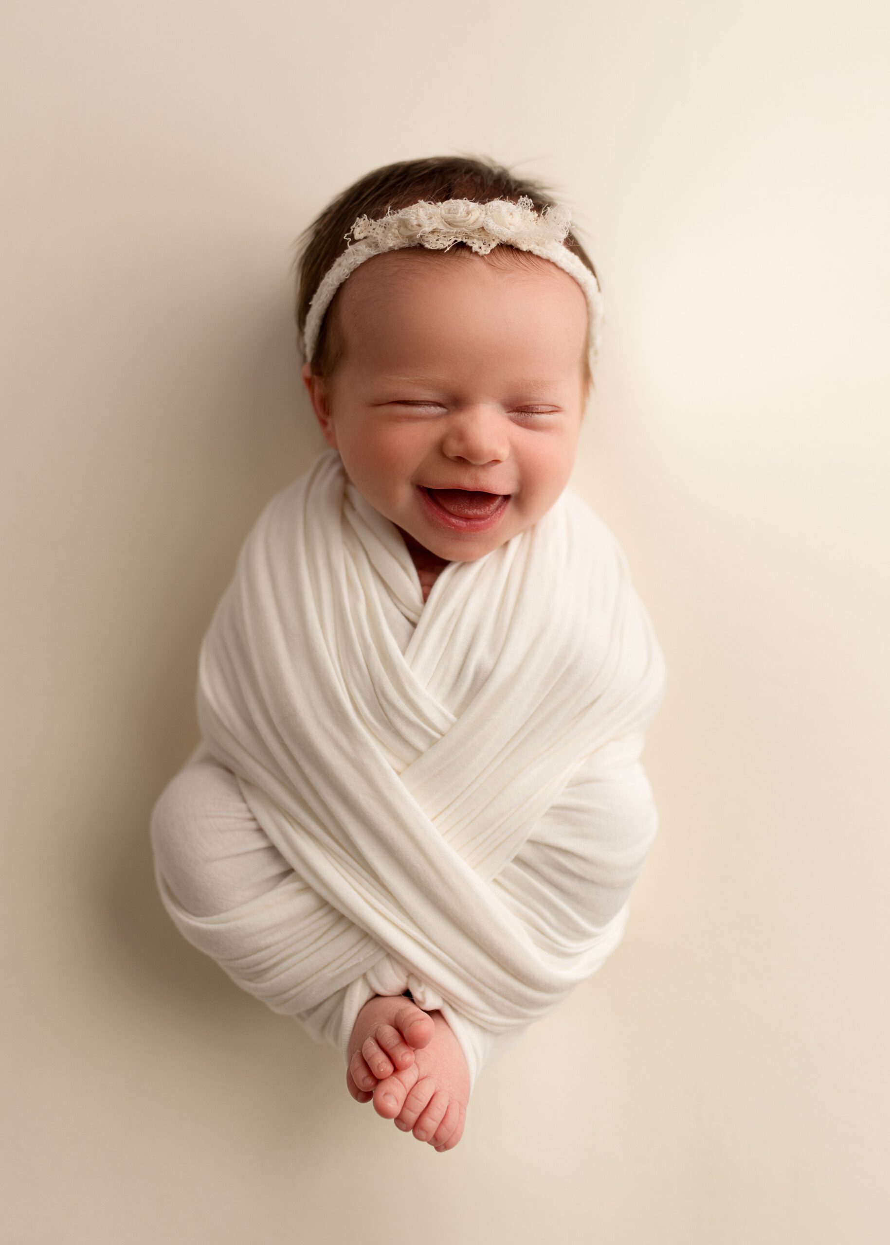 Swaddled Newborn baby girl smiling in Maria Angeles Photography Studio